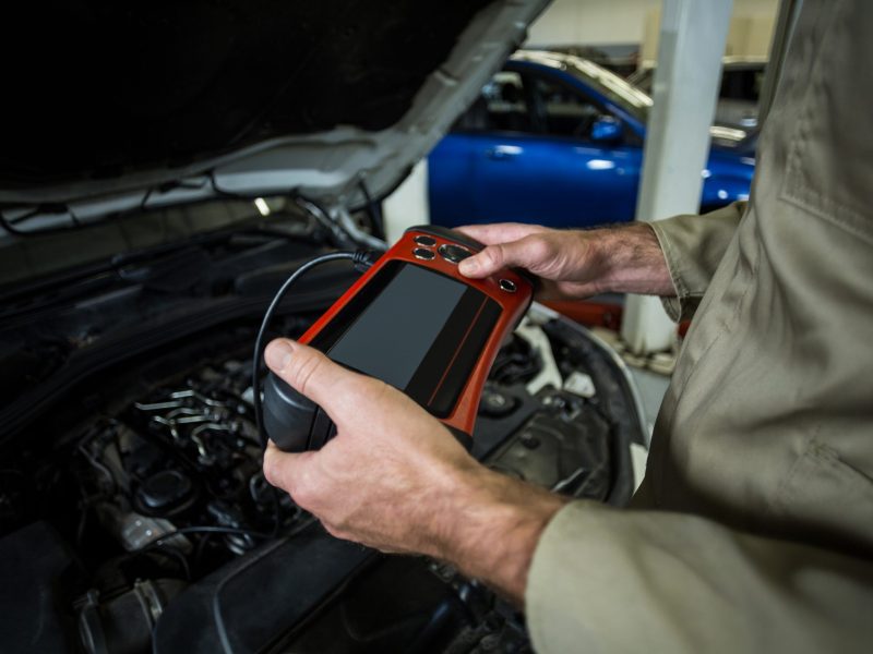 Hands of mechanic using a diagnostic tool in repair garage