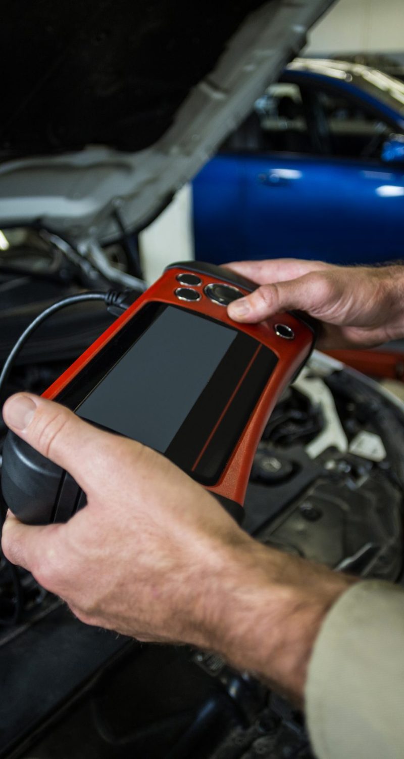 Hands of mechanic using a diagnostic tool in repair garage
